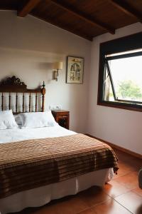 a bedroom with a large bed and a window at Casa de Afora Casa con piscina y jacuzzi privados in Santiago de Compostela