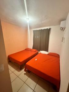 two beds in a room with orange sheets at Departamento en Acapulco Caleta in Acapulco