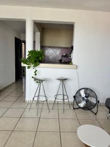 a kitchen with stools and a counter with a plant at Departamento en Acapulco Caleta in Acapulco