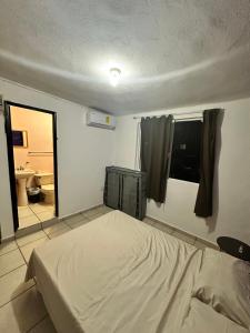 a bedroom with a bed and a bathroom with a mirror at Departamento en Acapulco Caleta in Acapulco +6 photos