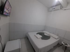a small white room with a bed and a tv at Pousada JM in Salgueiro