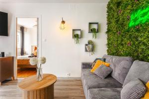 a living room with a couch and a green wall at Jungle Saintaise - Appartement, Hypercentre, Fibre, Tv 4K, Parking Privé Payant in Saintes