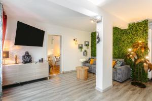 a living room with a couch and a tv on a wall at Jungle Saintaise - Appartement, Hypercentre, Fibre, Tv 4K, Parking Privé Payant in Saintes +11 photos