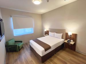 a bedroom with a bed and a green chair at DM Hoteles Nasca in Nazca