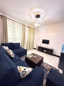 a living room with a blue couch and a tv at Beytumn Executive Apartment in Ruiru