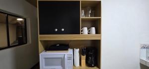 a cupboard with a microwave in a kitchen at Casa Petunia, Managua in Managua