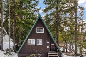 a small house with a triangular roof in the woods at Snowball House in Government Camp