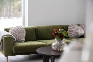 a green couch with a vase of flowers on a table at Charming Seaside Country Cottage in Myza Lakhetaguze