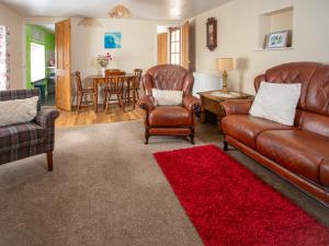 a living room with leather furniture and a red rug at The Bridge Inn Apartment in Bridgerule