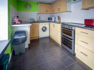 a kitchen with wooden cabinets and a washer and dryer at The Bridge Inn Apartment in Bridgerule