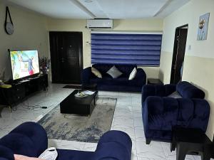 a living room with blue couches and a tv at Caligeo Suites I in Ibadan