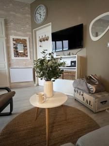 a living room with a table and a clock on the wall at L'horizon d'Ault, prêt à séjourner, draps & serviettes inclus, lits faits à l'arrivée in Ault +33 photos