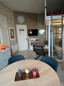 a room with a table and chairs and a clock on the wall at L'horizon d'Ault, prêt à séjourner, draps & serviettes inclus, lits faits à l'arrivée in Ault