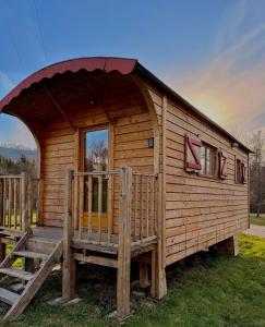 a wooden cabin with a large door and a porch at Camping l'Estela sur le GR70 in Le Monastier sur Gazeille