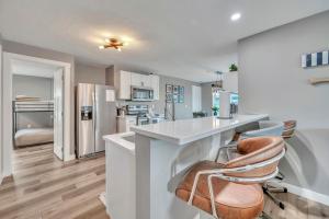 a kitchen with a white counter and stools at Okoboji BLUEtiful Cottage in Arnolds Park