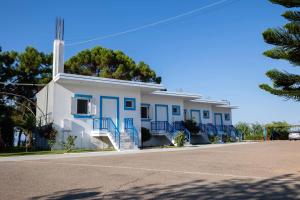 a white building with blue doors on a street at Kipriotis Hotel in Arkoudi