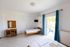 a room with a bed and a desk and a window at Kipriotis Hotel in Arkoudi