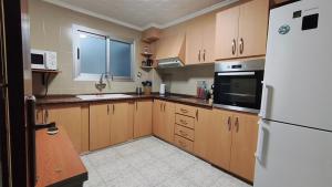 a kitchen with wooden cabinets and a white refrigerator at Piso Colon in Paiporta