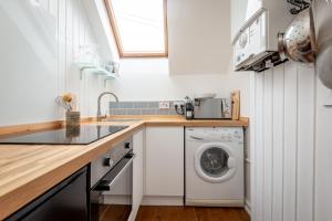 a kitchen with a washing machine and a sink at WeeLoft - St Andrews Studio Apartment in St. Andrews +32 photos