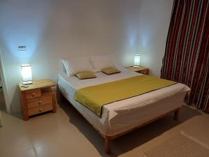 a bedroom with a bed and two night stands with lamps at Djerba Beach Haven in Aghīr