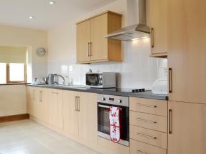 a kitchen with wooden cabinets and a stove top oven at The Smithy - Op6 in Carmarthen