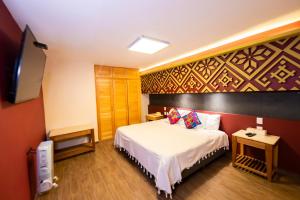 a hotel room with a bed and a flat screen tv at Hotel Uniko in San Cristóbal de Las Casas