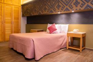 a bedroom with a large bed with a pink blanket at Hotel Uniko in San Cristóbal de Las Casas
