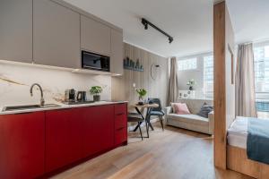 a kitchen with red cabinets and a living room at Pereca City Centre Studios by Arrenda in Warsaw