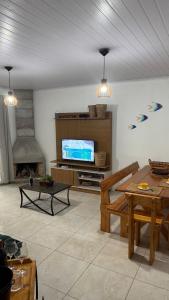 a living room with a television and a table at House on Hermenegildo Beach in Santa Vitória do Palmar