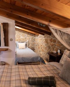 a bedroom with two beds and a stone wall at Petrino Lodge Stone Mountain Retreat in Kato Trikala Korinthias