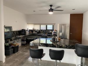 a kitchen with a counter with chairs and a ceiling fan at Otoch de Paz in Cholul