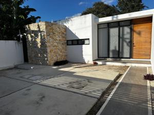 a white house with a wooden door and a driveway at Otoch de Paz in Cholul