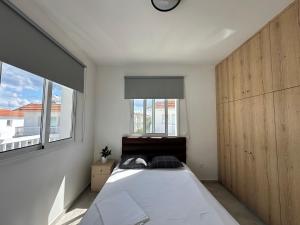 a bedroom with a large bed and two windows at Ocean Breeze 2BR House in Paralimni