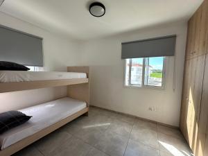 a bedroom with two bunk beds and a window at Ocean Breeze 2BR House in Paralimni