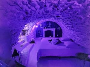 a purple room with a bed in a cave at L'epicurisme in Lorgues +3 photos