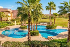 a pool with palm trees in a resort at Prestigia Family Luxury Apartments in Marrakesh