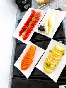 four white plates with different types of vegetables on them at Sun Route Hotel in Cabo de Santo Agostinho