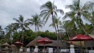 a group of palm trees and umbrellas on a beach at Kasa First Apartment in Mtwapa