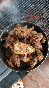 a pan full of meat cooking on a grill at Kasa First Apartment in Mtwapa