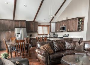 a living room with a leather couch and a kitchen at Grizzly Den in Valemount
