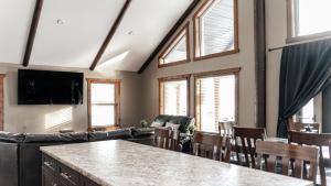a living room with a table and chairs and windows at Grizzly Den in Valemount