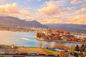a large container ship in a river with a city at Pacific Pearl in Vancouver