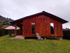 a red shed with a bear sitting in the grass at Cabaña Ortiz in Guatavita