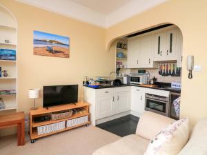 a kitchen with white cabinets and a tv in a room at 3 Dartview in Dartmouth