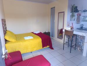 a bedroom with a yellow bed and a kitchen at Studio Jéssica in Arunta