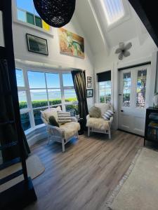 a living room with two chairs and large windows at The Point Studio in Nelson