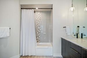 a bathroom with a tub and a shower with a sink at Timber & Tin C 2Bed 2Bath w Pool & Rooftop Deck in Kanab