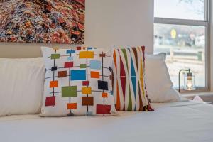 a bed with two colorful pillows on top of it at Timber & Tin C 2Bed 2Bath w Pool & Rooftop Deck in Kanab +101 photos