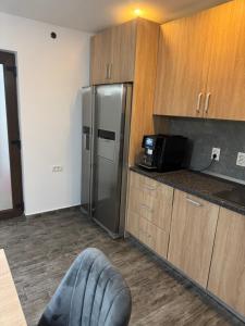a kitchen with a stainless steel refrigerator and wooden cabinets at Timi&Amos2 in Caransebeş +18 photos