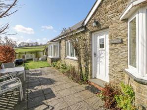 a brick house with a white door and a patio at Glanyrafon Smithy in Llandysul